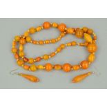 A NATURAL AMBER AND PLASTIC BEAD NECKLACE AND A PAIR OF NATURAL AMBER DROP EARRINGS, the necklace