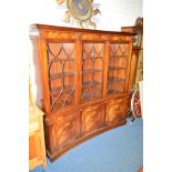 A REPRODUX MAHOGANY CONCAVE ASTRAGAL GLAZED THREE DOOR BOOKCASE above a triple cupboard door base,