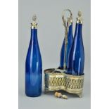 A PLATED THREE BOTTLE TANTALUS with trefoil shaped base and central handle and three blue glass