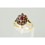 A 9CT GOLD GARNET CLUSTER RING designed as a central oval garnet within a circular garnet surroun to