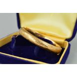 A 9CT GOLD MID TWENTIETH CENTURY OVAL HINGED BANGLE, half engraved to one side, hallmarked 9ct gold,