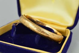 A 9CT GOLD MID TWENTIETH CENTURY OVAL HINGED BANGLE, half engraved to one side, hallmarked 9ct gold,