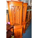 TWO YEW WOOD GLAZED CORNER CUPBOARDS, together with a three drawer bedside chest (bedside chest
