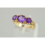 A MID TO LATE 20TH CENTURY THREE STONE AMETHYST RING, scroll detail to shoulders and sides, ring