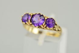 A MID TO LATE 20TH CENTURY THREE STONE AMETHYST RING, scroll detail to shoulders and sides, ring