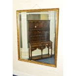 A LARGE GILT AND FOLIATE FRAMED BEVELLED EDGE WALL MIRROR, 116cm x 147cm