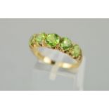 A 9CT GOLD FIVE STONE PERIDOT RING, the central largest round mixed cut peridot measuring 5.5mm x