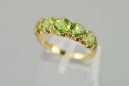 A 9CT GOLD FIVE STONE PERIDOT RING, the central largest round mixed cut peridot measuring 5.5mm x