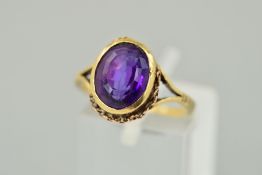 AN AMETHYST RING, the oval amethyst within a collet setting to the belcher link surround (partly