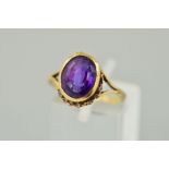 AN AMETHYST RING, the oval amethyst within a collet setting to the belcher link surround (partly