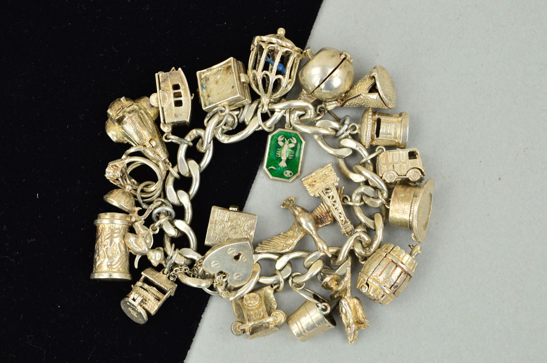 A SILVER CHARM BRACELET AND CHARMS, the curb link bracelet suspending 21 charms, to include a hinged