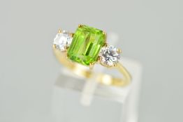 A 9CT GOLD PERIDOT RING, the central rectangular peridot within a four claw setting flanked by