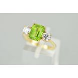 A 9CT GOLD PERIDOT RING, the central rectangular peridot within a four claw setting flanked by