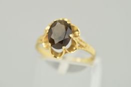 A 9CT GOLD SMOKY QUARTZ RING, the oval smoky quartz within a scalloped claw setting to the