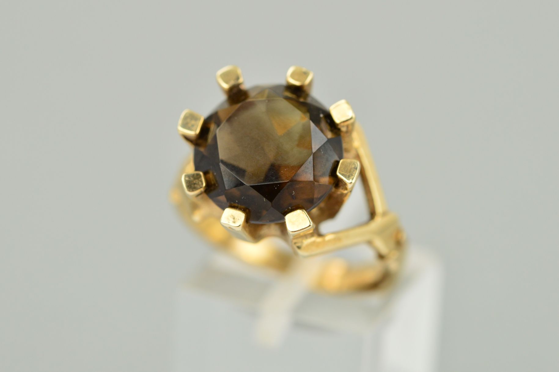 A 9CT GOLD SMOKY QUARTZ RING, the circular smoky quartz within a thick eight claw setting with a