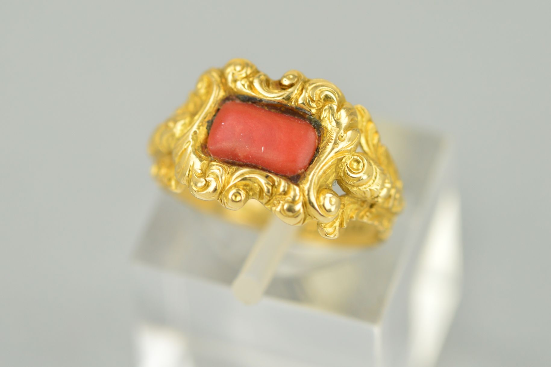 A LATE GEORGIAN GOLD AND CORAL RING, centering on rectangular coral stone (which is a likely later