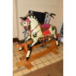 AN EARLY 20TH CENTURY CARVED WOODEN ROCKING HORSE, cream ground with dappled black markings,