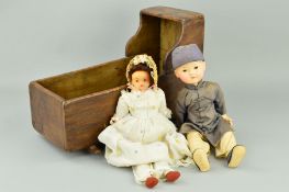 A WOODEN DOLLS CRIB, containing an Oriental style composition doll, painted features, moulded
