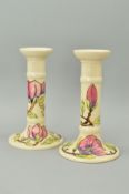 A PAIR OF MOORCROFT POTTERY CANDLESTICKS, 'Magnolia' pattern on cream ground, impressed and