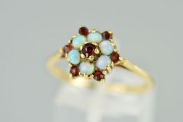 A 9CT GOLD OPAL AND GARNET CLUSTER RING designed as a central circular garnet within an opal