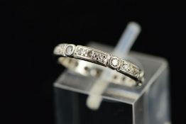 A DIAMOND ETERNITY RING designed as rectangular and circular panels set with single cut diamonds,