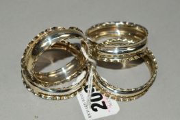 FOUR CIRCULAR SILVER NAPKIN RINGS WITH WAVY RIMS, hallmarks for Chester and Birmingham, partially