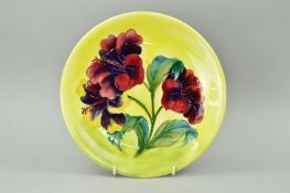 A MOORCROFT POTTERY PLATE, 'Hibiscus' pattern on yellow ground, impressed and paper labels to