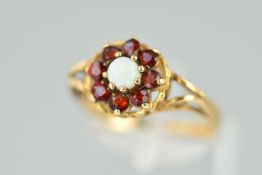 A 9CT GOLD OPAL AND GARNET RING, designed as a central circular opal cabochon within a circular