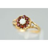 A 9CT GOLD OPAL AND GARNET RING, designed as a central circular opal cabochon within a circular