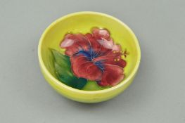 A SMALL MOORCROFT POTTERY FOOTED BOWL, 'Hibiscus' pattern on yellow/green ground, impressed