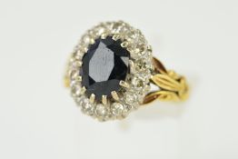 A LATE 20TH CENTURY 18CT GOLD SAPPHIRE AND DIAMOND OVAL CLUSTER RING centering on a dark blue oval
