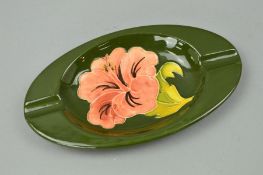 A MOORCROFT POTTERY OVAL SHAPED ASHTRAY, 'Hibiscus' pattern on green ground, impressed marks to
