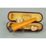 AN EARLY 20TH CENTURY NATURAL AMBER CHEROOT AND TWO RINGS, the cheroot with silver mount and