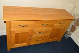 A MODERN LIGHT OAK SIDEBOARD with five various drawers and double cupboard doors, width 138cm x