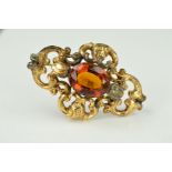 A LATE VICTORIAN CITRINE BROOCH of openwork scrolling design centrally set with an oval citrine,