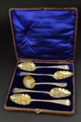 A CASED HARLEQUIN SET OF FOUR GEORGIAN SILVER BERRY SPOONS AND CASTER SPOON, gilt bowls embossed