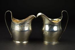 TWO GEORGE III SILVER BATEMAN CREAM JUGS, of helmet form, both with strap handles, one plain with