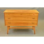 AN ALFRED COX WALNUT CHEST OF THREE LONG GRADUATING DRAWERS, on a teak stretchered base, width 109cm