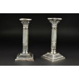 A NEAR PAIR OF ELIZABETH II SILVER CORINTHIAN COLUMN CANDLESTICKS, detachable shaped square beaded