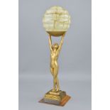 AN ART DECO NUDE FIGURAL LAMP, the female figure is holding aloft a smoke glass pattern shade,