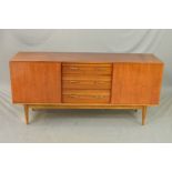 A WRIGHTON 1960’S TEAK SIDEBOARD, flanked by single cupboard doors and three long central drawers on