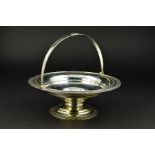 A GEORGE V CIRCULAR SILVER SWING HANDLED CAKE BASKET, the handle with central oval rosette, the