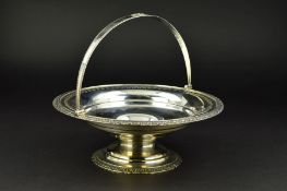 A GEORGE V CIRCULAR SILVER SWING HANDLED CAKE BASKET, the handle with central oval rosette, the