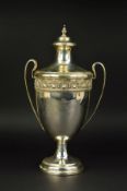 A GEORGE V TWIN HANDLED TROPHY CUP AND COVER, knopped finial over domed cover, the cup with cast rim