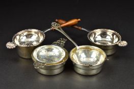 FOUR ELIZABETH II SILVER TEA STRAINERS AND STANDS, two on turned wooden handles with cast shell rest
