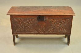 AN 18TH CENTURY OAK COFFER, the single plank top with chip carved ends, the front carved with