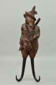 A 19TH CENTURY BLACK FOREST CARVED FOX MUSICAL COAT HOOK, modelled as wearing feathers in his hat,