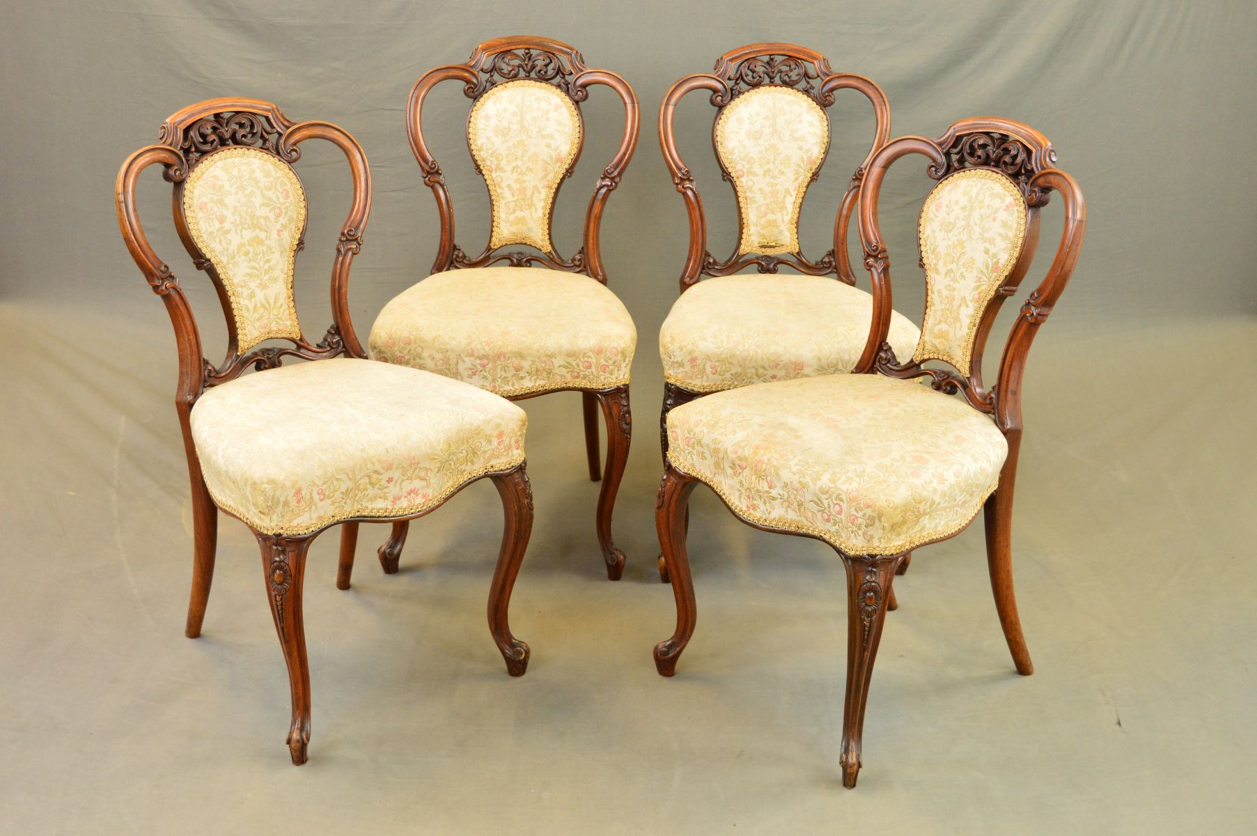 A SET OF FOUR VICTORIAN WALNUT DINING CHAIRS, the serpentine top rail above central foliate
