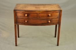 AN EARLY 19TH CENTURY MAHOGANY AND EBONY STRUNG BOW FRONT SIDE TABLE, fitted with two short and