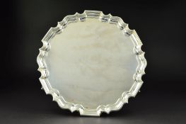 AN EDWARDIAN SILVER SALVER, of circular form with wavy pie crust border, no inscriptions, on three